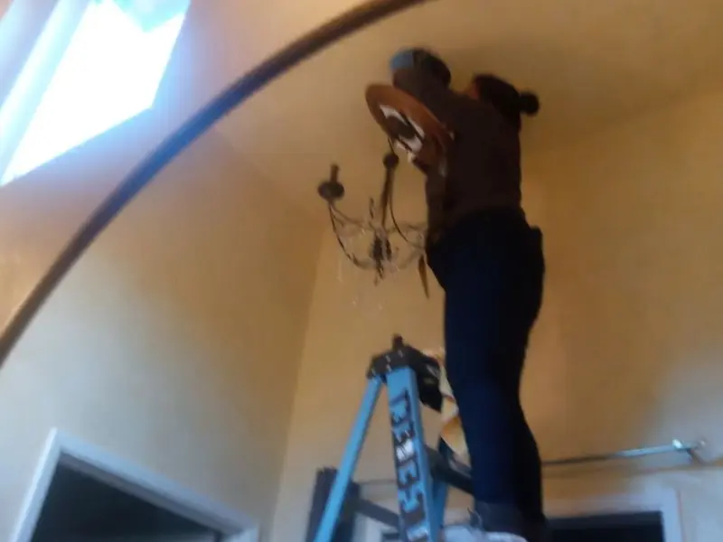Electrician installing a chandelier in a Cherry Creek residence